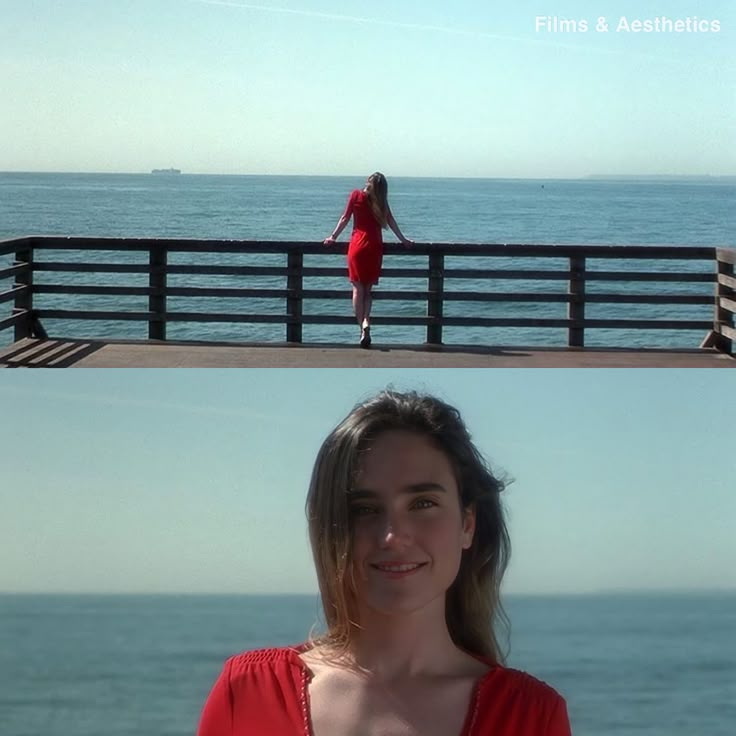 a woman in a red dress standing on a pier next to the ocean and looking at the camera