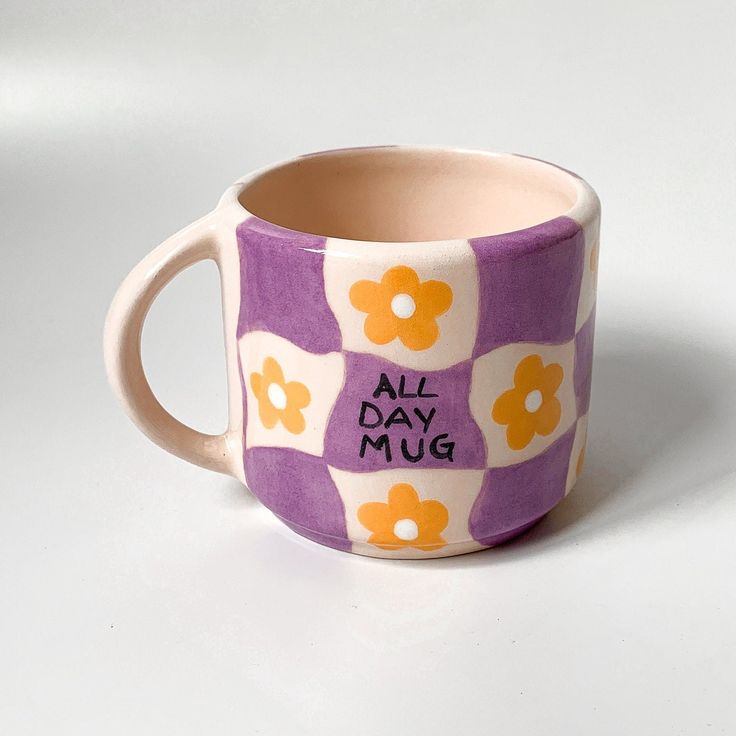 a purple and white coffee cup with flowers on the inside, says all day mug