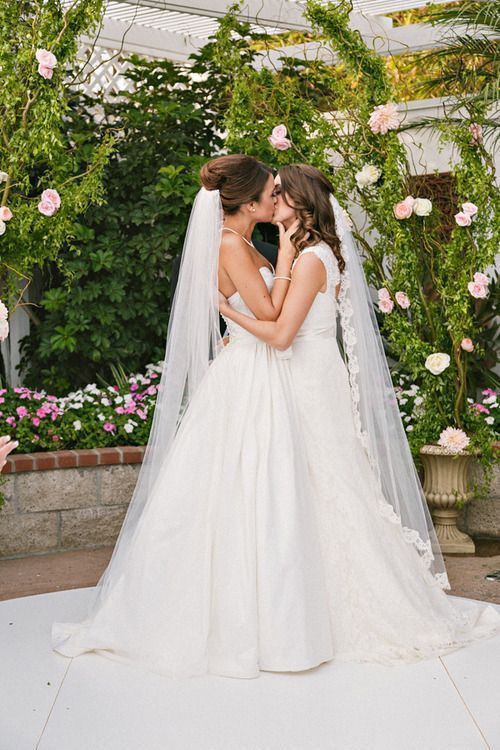 the bride and groom are kissing in front of flowers