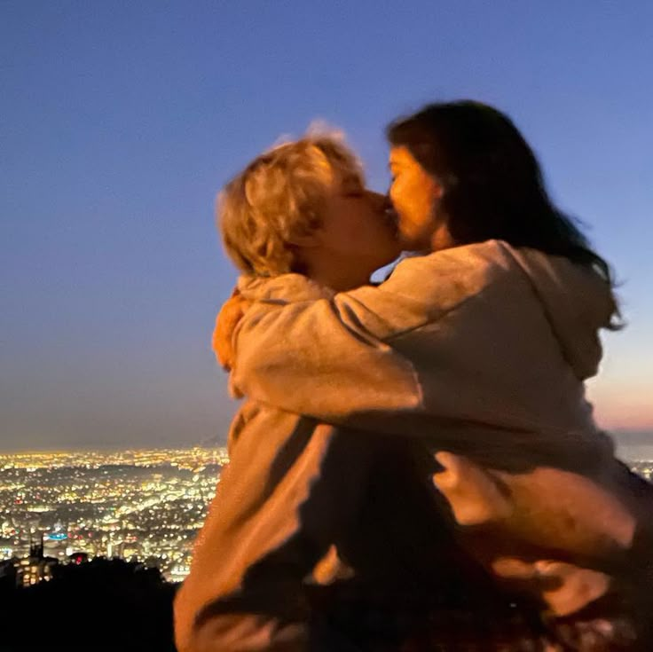 two people kissing each other in front of the city lights