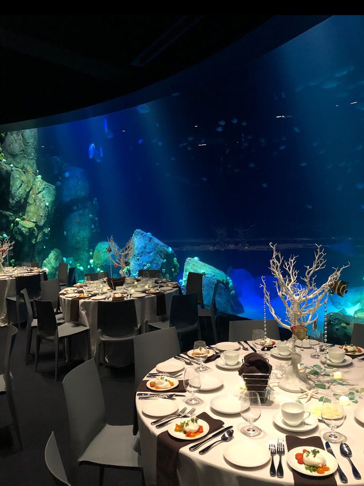 an aquarium is shown with tables set for dinner