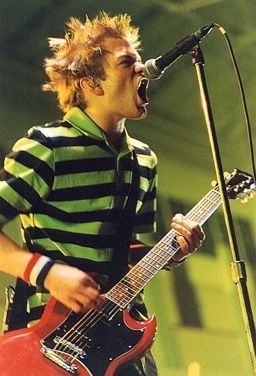 a young man singing into a microphone while holding a guitar in front of his face