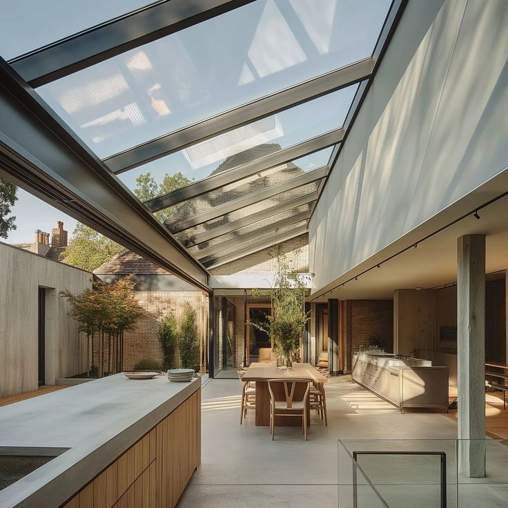 an outdoor kitchen and dining area with skylights on the roof, surrounded by glass walls