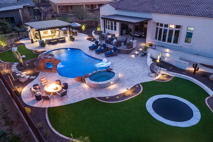 an aerial view of a backyard with a swimming pool and fire pit at night time