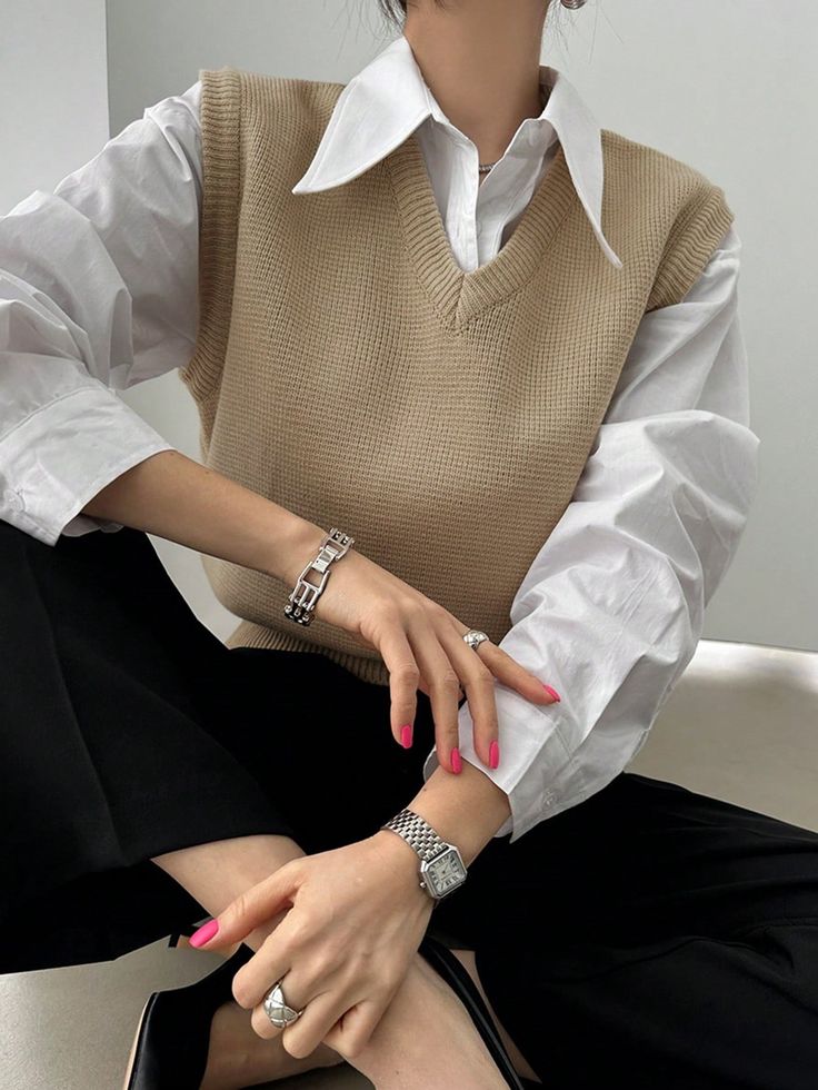 a woman sitting on top of a white couch wearing a brown sweater and black skirt