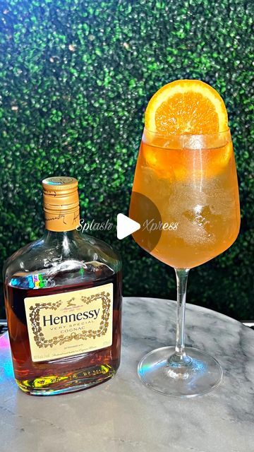 a bottle of hennessy next to a glass with an orange slice in it