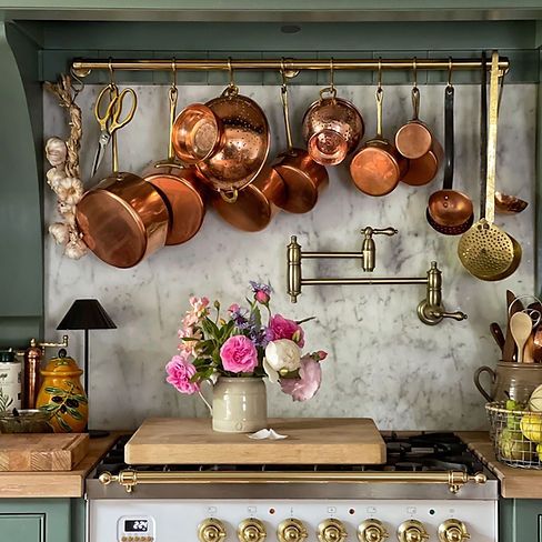 pots and pans are hanging on the wall above an oven