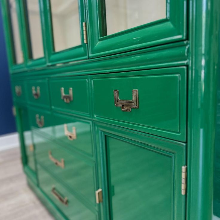 a green dresser with brass handles and drawers