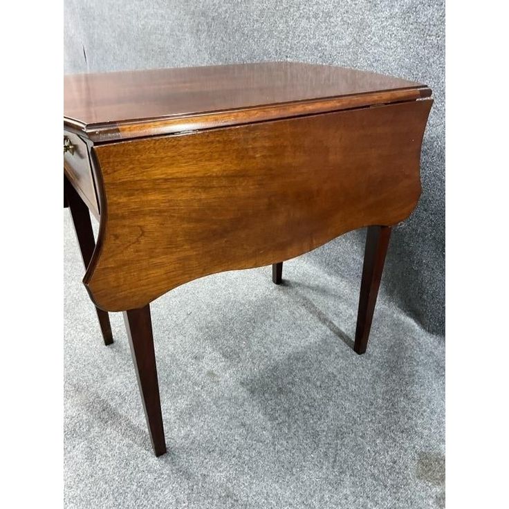 an old wooden desk sitting on top of a carpeted floor next to a wall