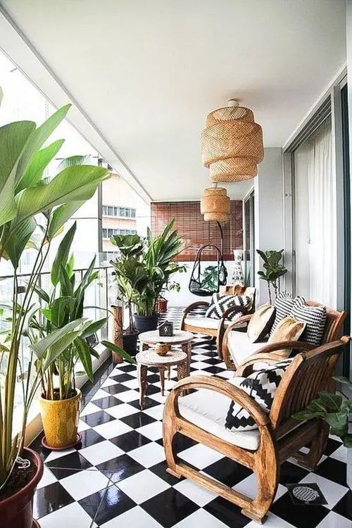 a black and white checkered floor with potted plants on the balcony, next to two wicker chairs