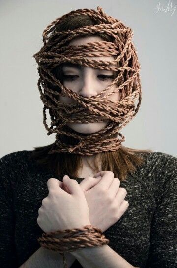 a woman with long hair tied up to her face and hands in front of her