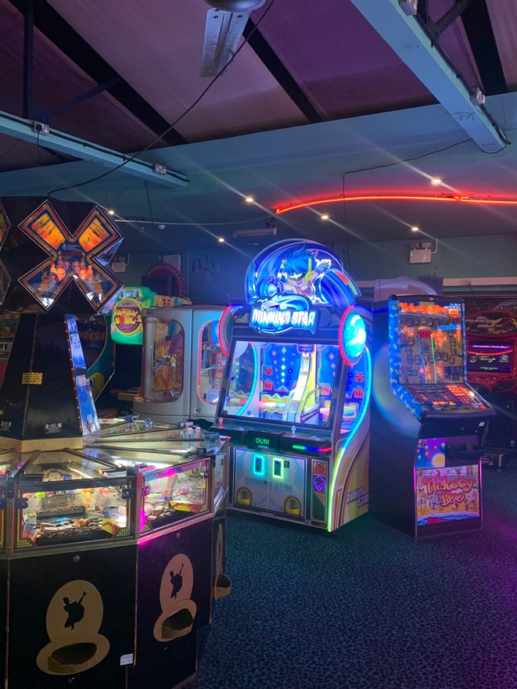 several arcade machines lined up in a room with neon lights on the ceiling and floor