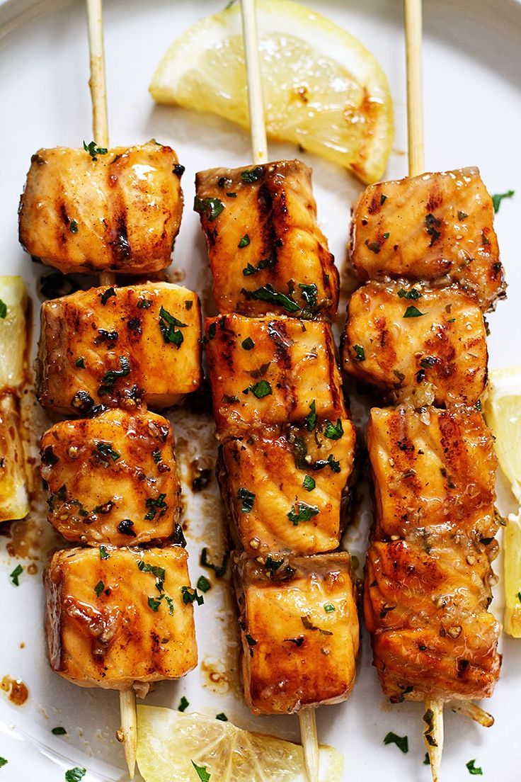 chicken skewers with lemon and parsley on a white plate