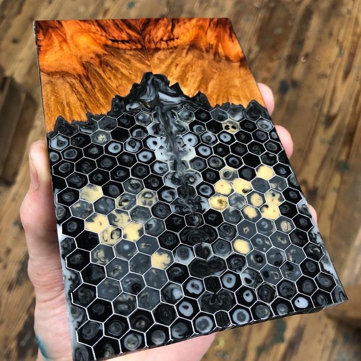 a person holding up a piece of wood with hexagons and honeycombs on it