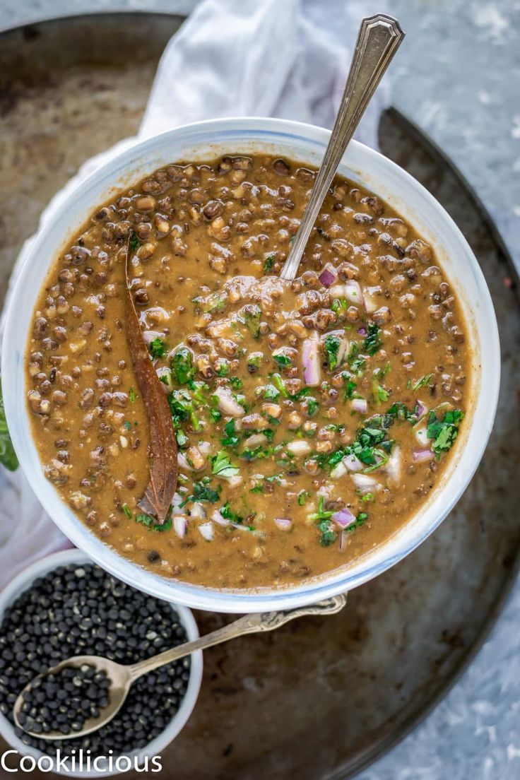 a white bowl filled with lentula soup next to black beans and a spoon in it