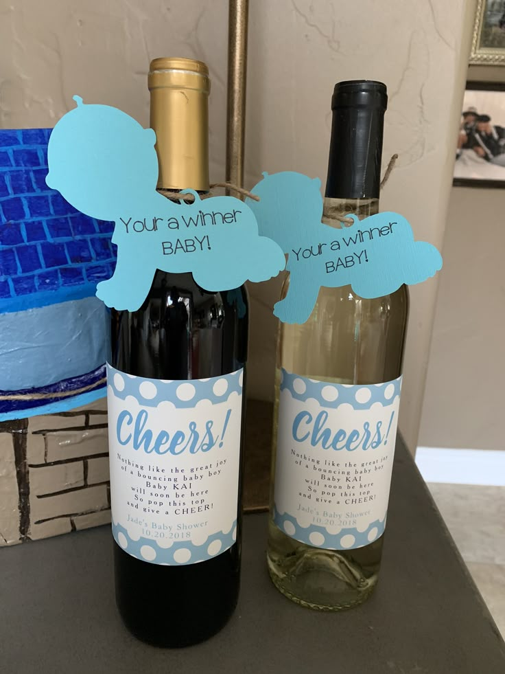 two bottles of wine sitting next to each other on top of a table with paper cutouts