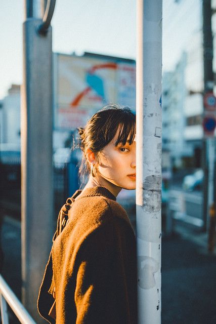 a woman leaning against a pole on the street