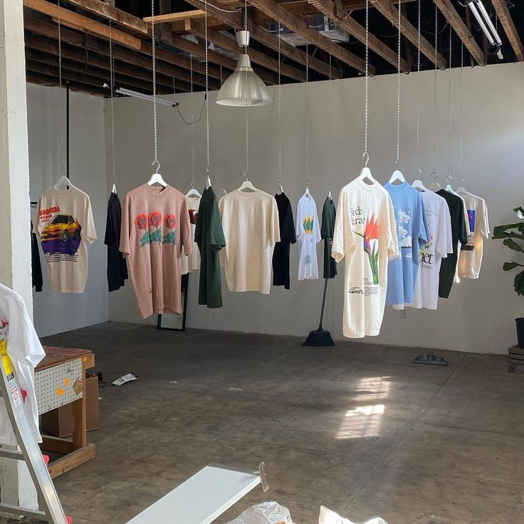 several t - shirts are hanging in an empty room