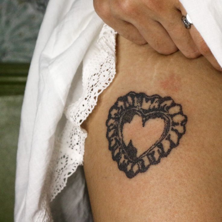 a woman with a heart tattoo on her thigh, holding onto the side of her stomach