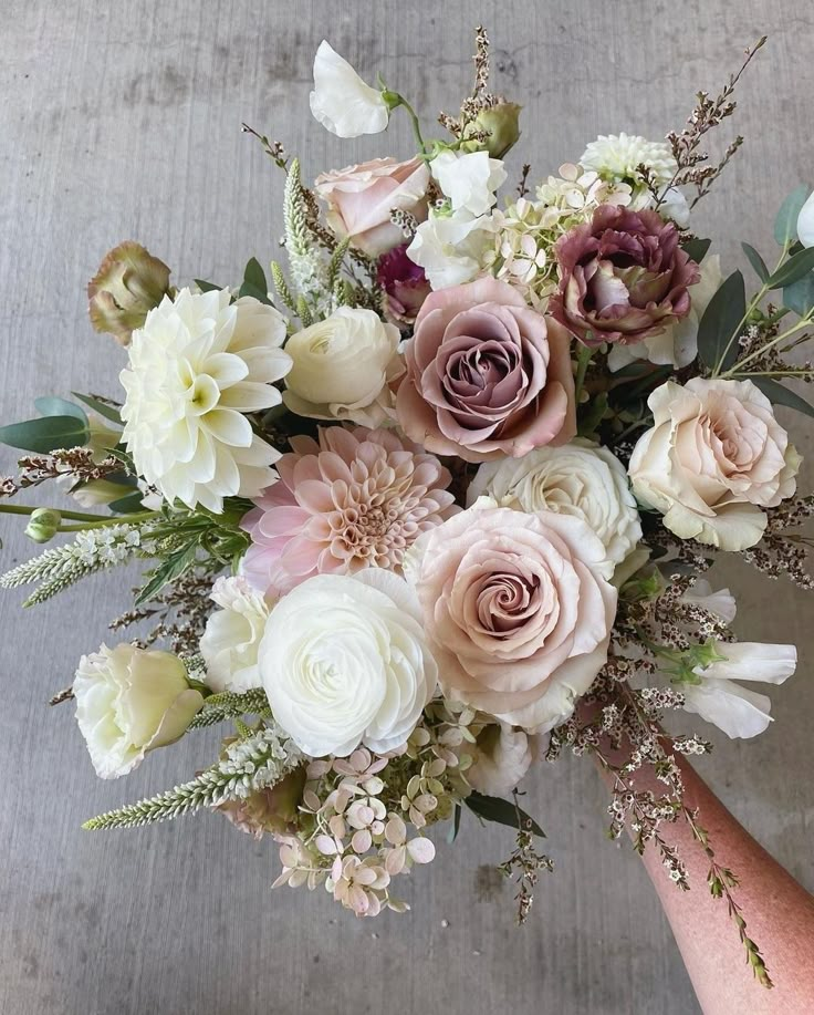 a bouquet of flowers is being held by someone's hand in front of the camera