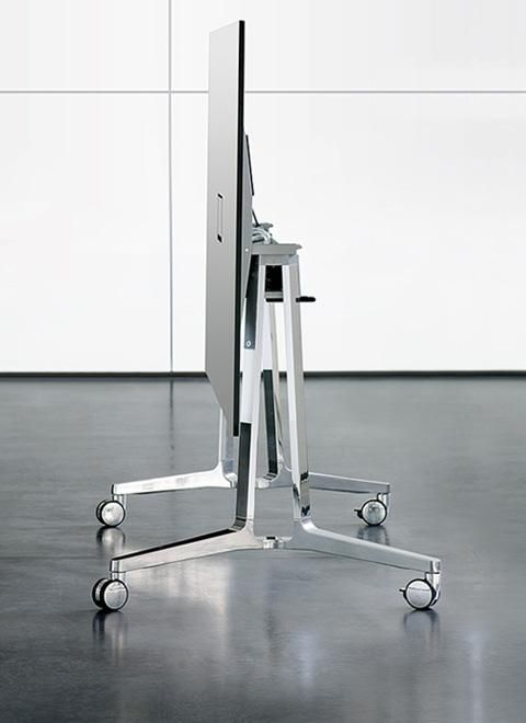 a computer monitor sitting on top of a metal stand in front of a white wall