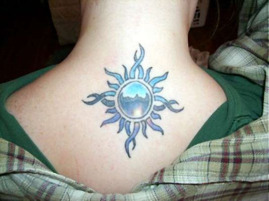 the back of a woman's neck with a sun tattoo on her left side