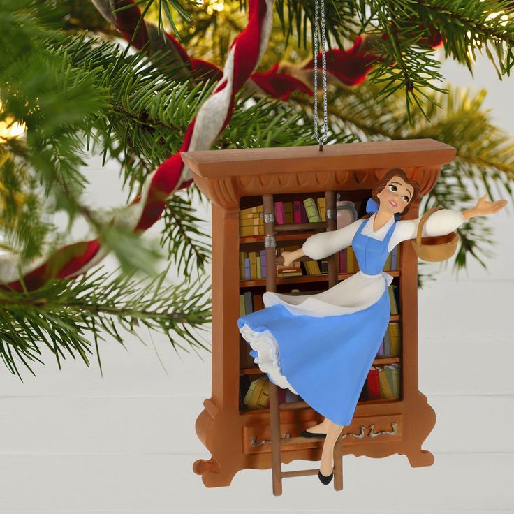 a christmas ornament hanging from a tree with bookshelf in the background