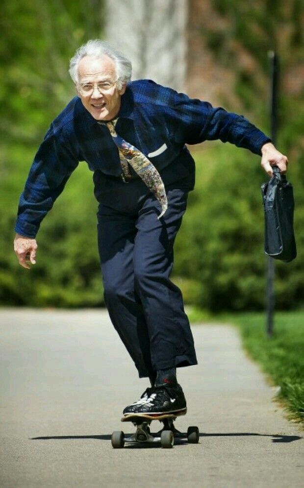 an old man riding a skateboard down a street next to a sign that says moments