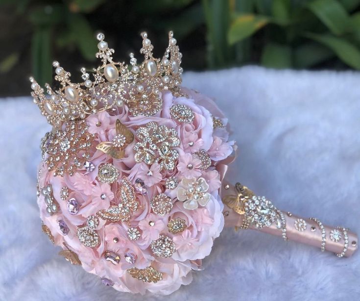 a bridal bouquet with pink flowers and gold tiara on a white furnishing