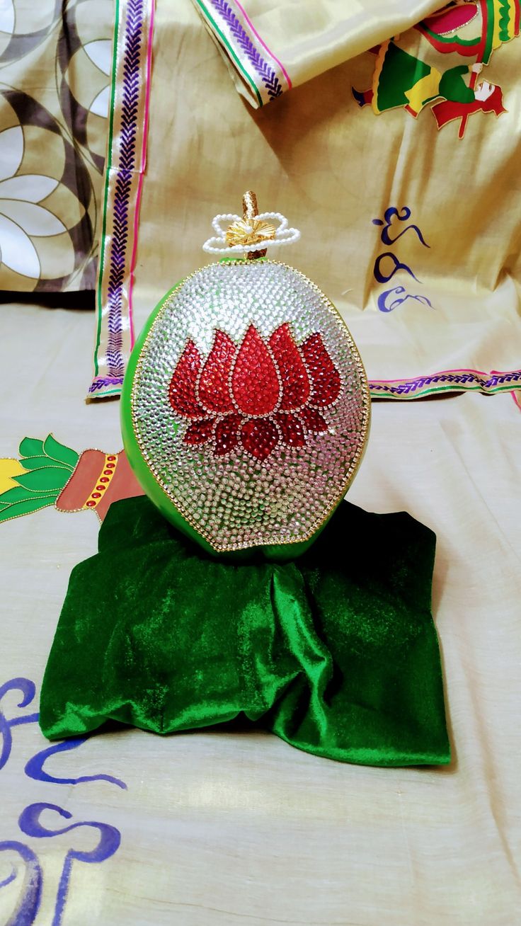 a green bag with red flowers on it sitting on top of a cloth covered table