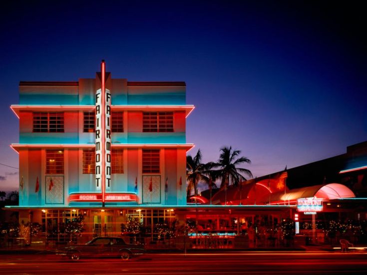 a large building with neon lights on it's sides and palm trees in the background