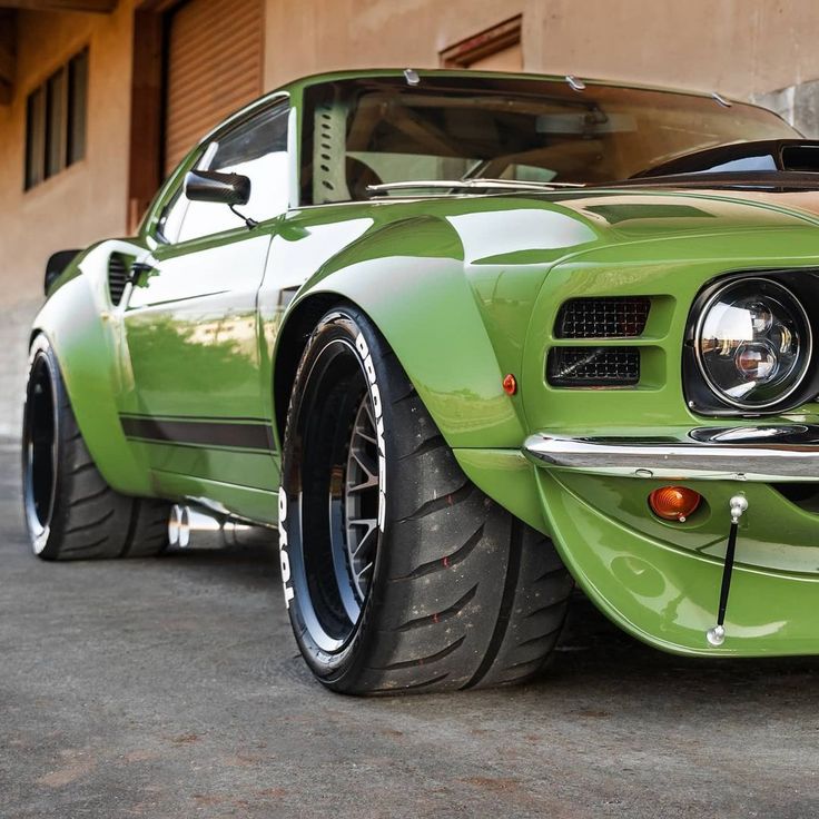 a green muscle car parked in front of a building