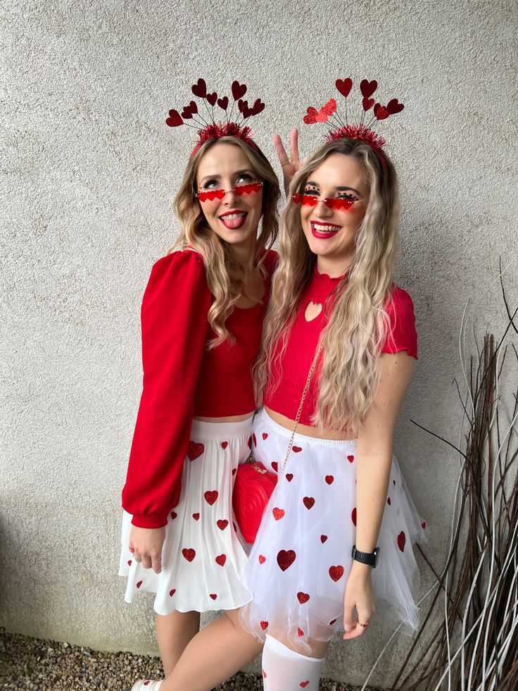 two girls dressed up in costumes with hearts on their faces and red heart - shaped glasses