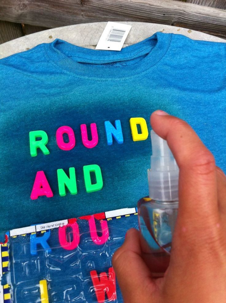 a person holding a spray bottle near a t - shirt with the words round and you on it