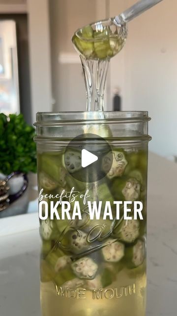 a jar filled with pickles and water on top of a kitchen counter next to a potted plant