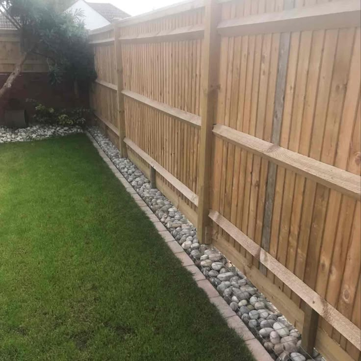 a backyard with grass, rocks and wooden fence