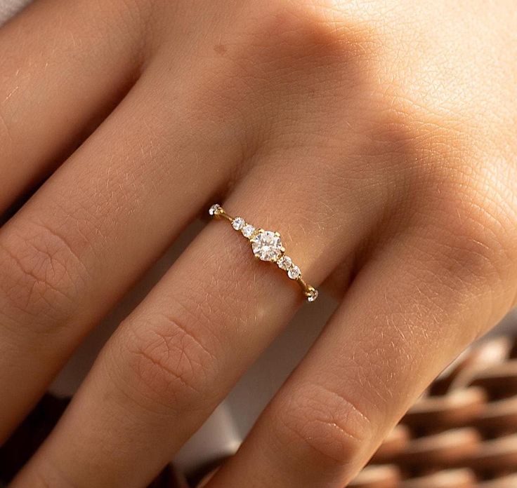 a woman's hand with a diamond ring on top of her finger and the bottom half of her fingers