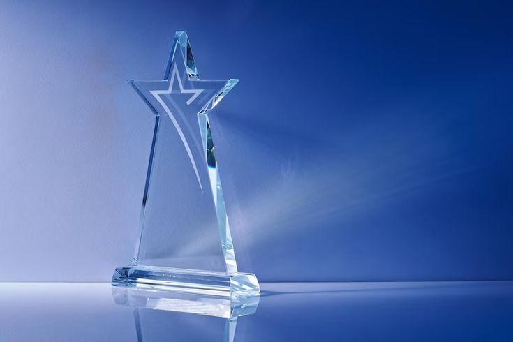 a clear glass trophy with a star on it's side, against a blue background