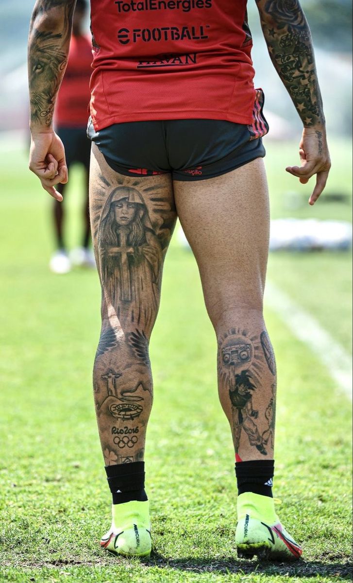 a man with tattoos on his legs standing in the grass