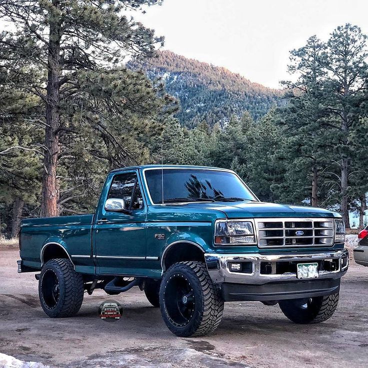 a blue pickup truck parked in front of some trees