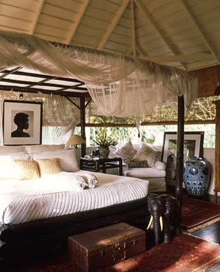 a canopy bed sitting in the middle of a living room next to a table and chairs