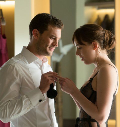 a man and woman standing next to each other in front of a dress rack with clothing on it