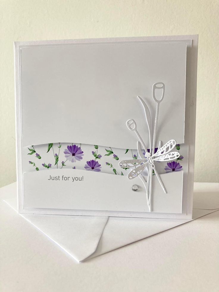 a white card with purple flowers and scissors on it, next to a pair of scissors