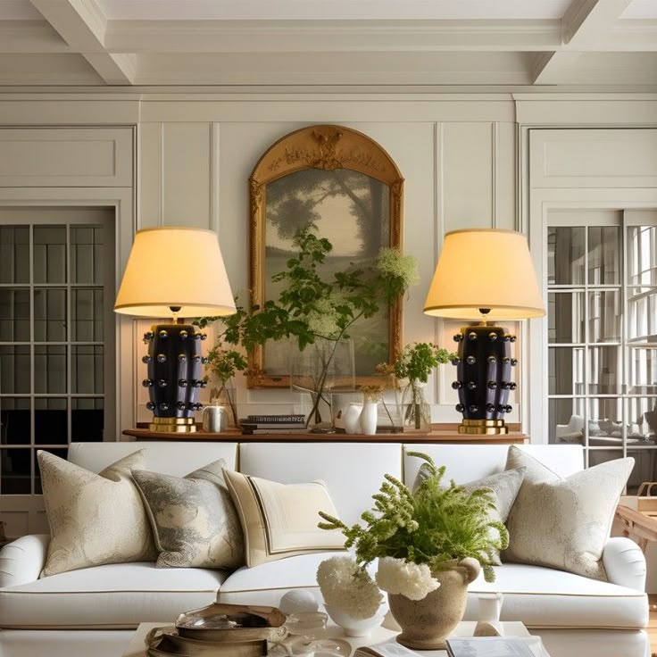 a living room filled with white furniture and two lamps on top of it's tables