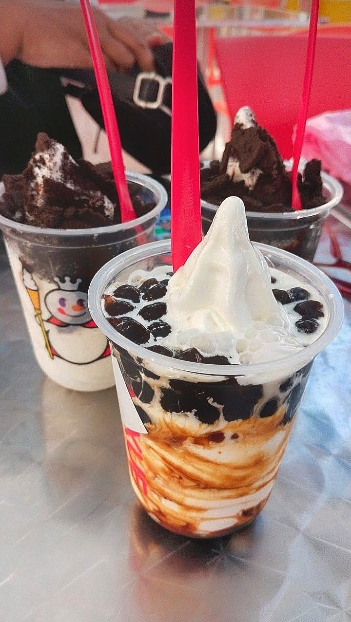 two ice cream sundaes with chocolate pudding and whipped cream on top, sitting on a table