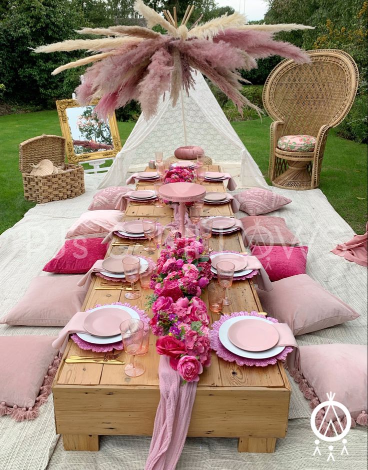 a table set up with pink flowers and place settings for an outdoor dinner or bridal party