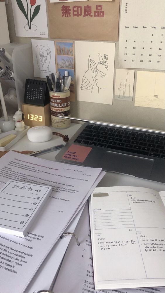 a laptop computer sitting on top of a desk next to papers and other office supplies