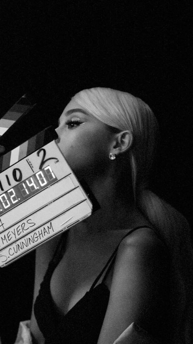 a black and white photo of a woman holding a movie clapper over her face