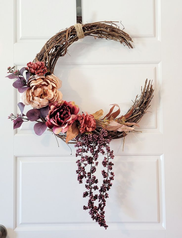 a wreath with dried flowers hanging on the front door to decorate it for fall or halloween