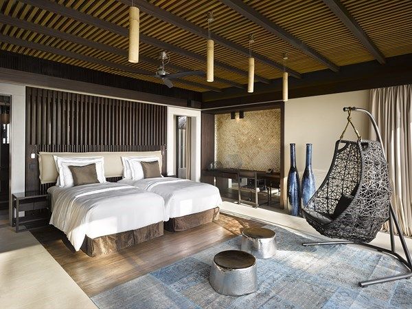 two beds in a room with wooden ceiling and white bed linens on the floor